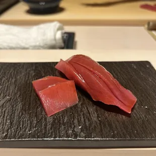 two pieces of raw fish on a black plate