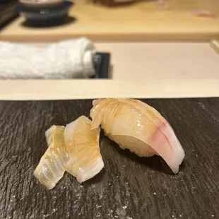 two pieces of sushi on a black plate