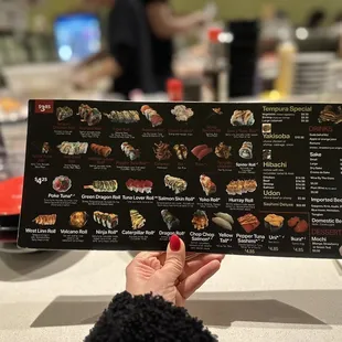 a person holding up a sushi menu