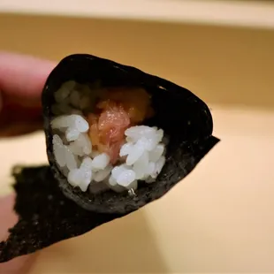 a hand holding a piece of sushi