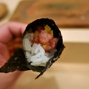 a hand holding a piece of sushi