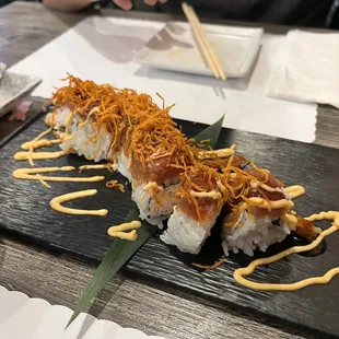 a sushi on a black plate with chopsticks