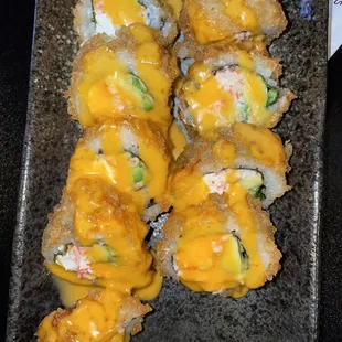 a platter of sushi rolls with cheese sauce