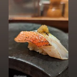 a piece of sushi on a black plate