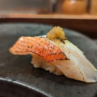 a piece of sushi on a black plate