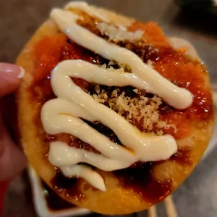 a person holding a small pizza with sauce on it