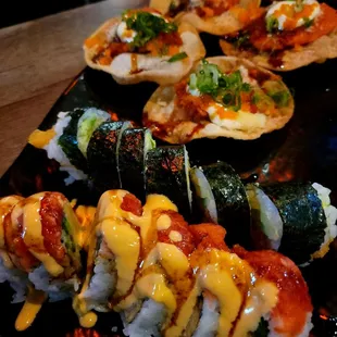 a variety of sushi rolls on a black plate