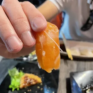 a person holding a piece of sushi