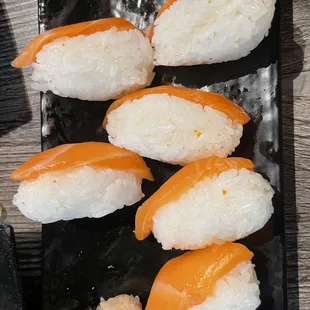 four pieces of sushi on a black plate