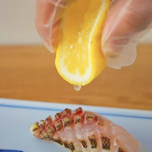 a person squeezing a slice of lemon