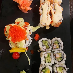 various types of sushi on a black plate