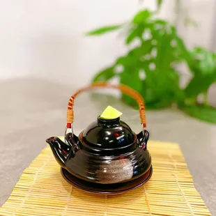 a black teapot on a bamboo mat