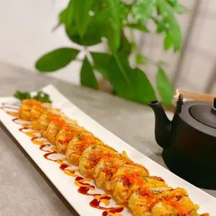a sushi roll with sauce and a teapot