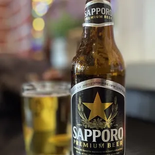 a bottle of sapporo beer next to a glass of beer