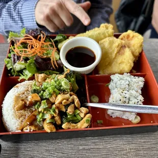 a tray of food with rice, meat, and vegetables