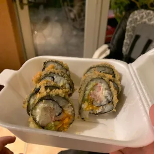 two sushi rolls in a styrofoam container
