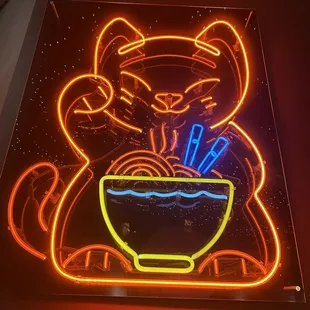 a neon sign of a cat holding a bowl of noodles