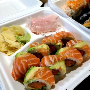 a variety of sushi in a styrofoam container