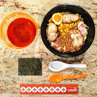 Tan Tan Men ramen noodles with pork before assembly. The reddish broth is on the left. Dried seaweed is the black rectangle.