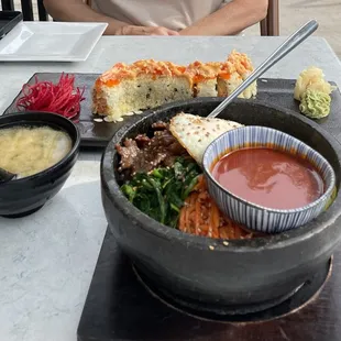 a man sitting at a table with a bowl of sushi and a bowl of soup