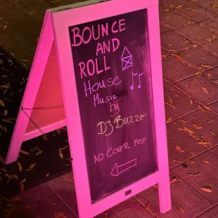 a pink sign on a sidewalk
