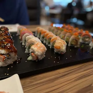 a variety of sushi on a black plate