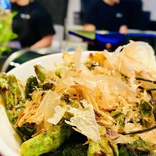 Shisito Peppers, stir fried with garlic soy butter and topped with bonito.