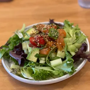 a bowl of salad on a wooden table