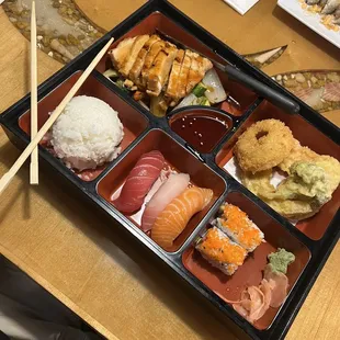 a tray of sushi with chopsticks