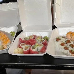 three take out containers with different types of sushi