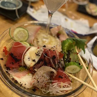 a bowl of sushi with chopsticks