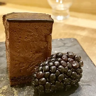 a piece of chocolate cake and a blackberry