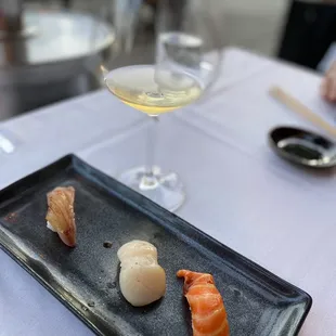 a plate of sushi and a glass of wine