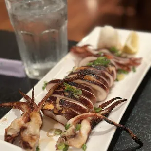 a plate of squid with a glass of water