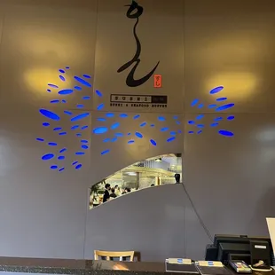 a sushi restaurant counter with blue fish on the wall