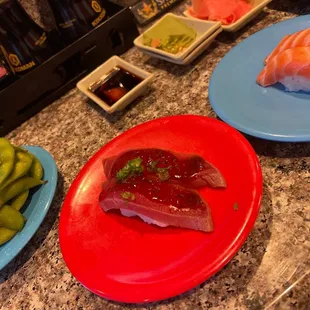 three plates of sushi on a granite countertop