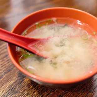 a bowl of soup with a red spoon