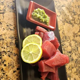 a plate of raw tuna and a slice of lemon