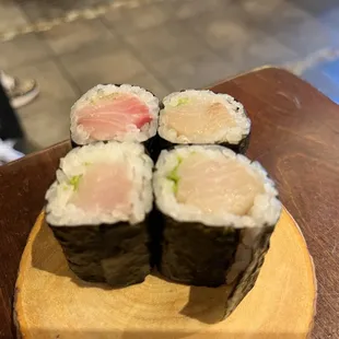 four pieces of sushi on a wooden plate