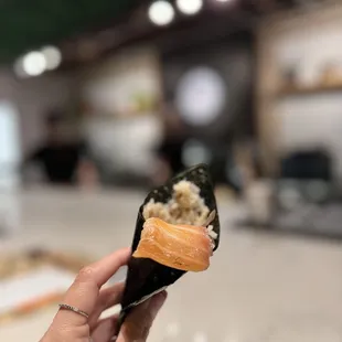 a hand holding a piece of sushi