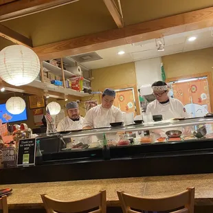 three chefs preparing food in a restaurant