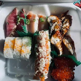 a variety of sushi in a styrofoam container