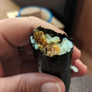 a hand holding a piece of sushi