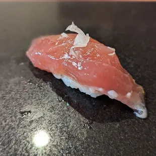 a piece of sushi on a black surface