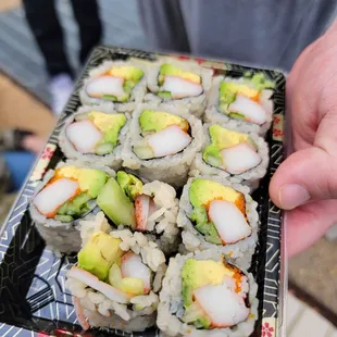 a person holding a plate of sushi