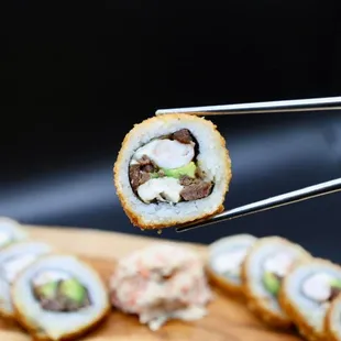 a piece of sushi being held by a pair of tongs