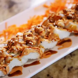 a plate of sushi topped with sauce and nuts