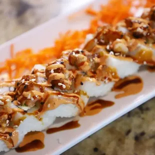 a plate of sushi with sauce and vegetables