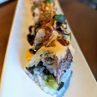 Hamachi Fever roll. $16. Inside: shrimp tempura, avocado. Top: Seared yellowtail, microgreens, garlic chips, Sriracha aioli, sweet soy.