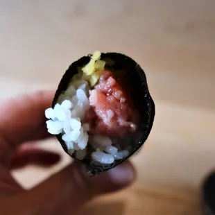 a hand holding a piece of sushi